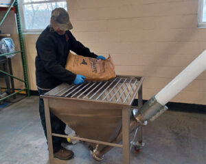 Engineer loads powder into hopper of AFC Spiralfeeder flexible screw conveyor