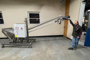 AFC Tiltable Spiralfeeder screw conveyor shown tilted in AFC test lab with operator